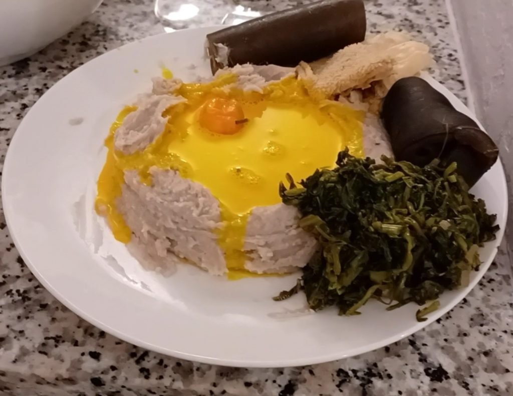 Achu served on a white dish on a gray kitchen slab.