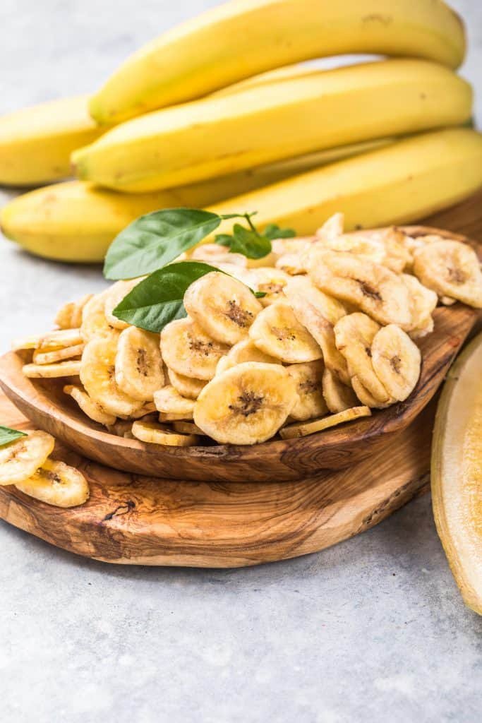 Whole and sliced bananas on a wooden board