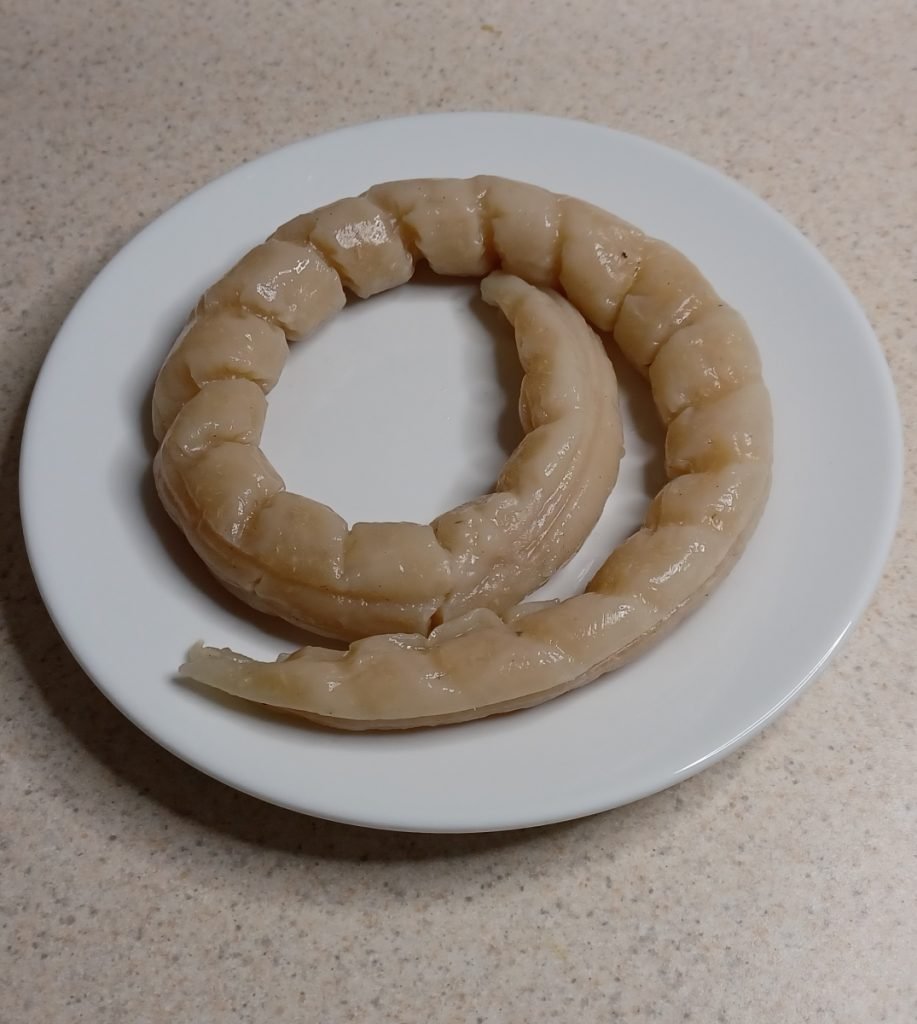 Bobolo in a white dish on a white kitchen slab.