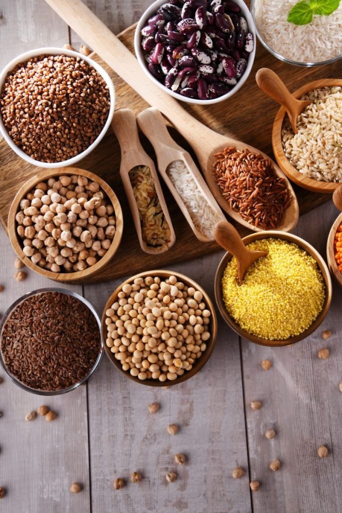 Beans, lentils, peas and other fiber rich grains on a brown wooden table.