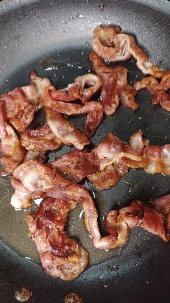 Fried bacon in a frying pan.