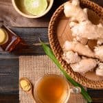 Ginger tea, ginger roots, limes and honey on a wooden table.
