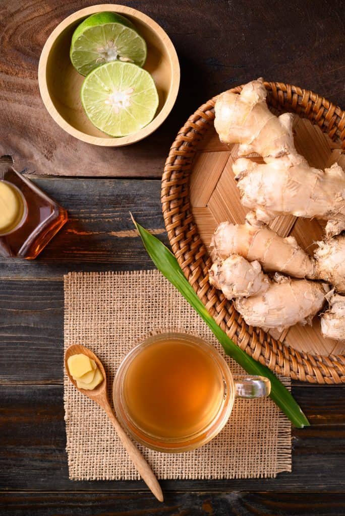 Ginger tea, ginger roots, limes and honey on a wooden table.