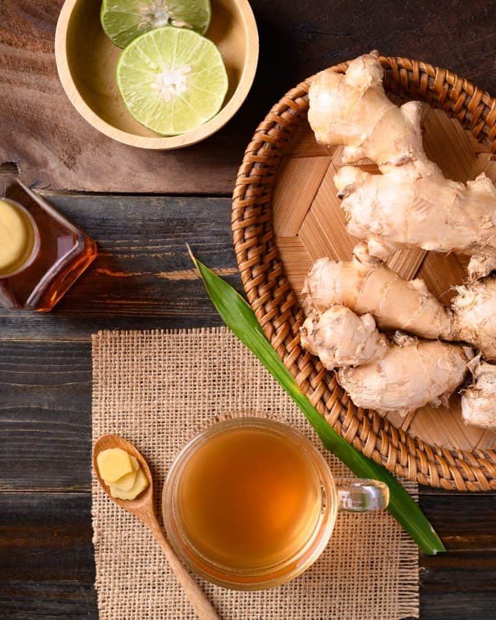 Ginger tea, ginger roots, limes and honey on a wooden table.