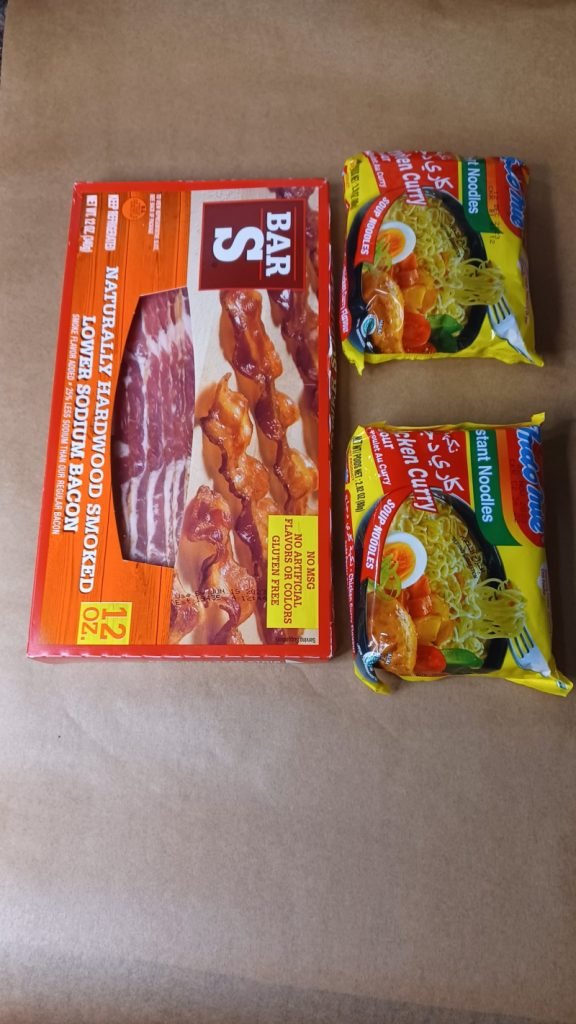 Ingredients for bacon noodles on a brown background.