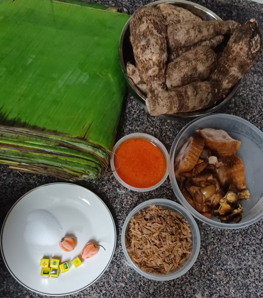 Taro, smoked turkey, crayfish, palm oil, plantain leaves and spices on a gray kitchen slab.