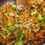 Mushroom stir fry and wooden spoon in a pot.