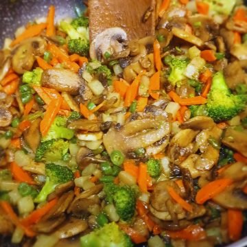 Mushroom stir fry and wooden spoon in a pot.