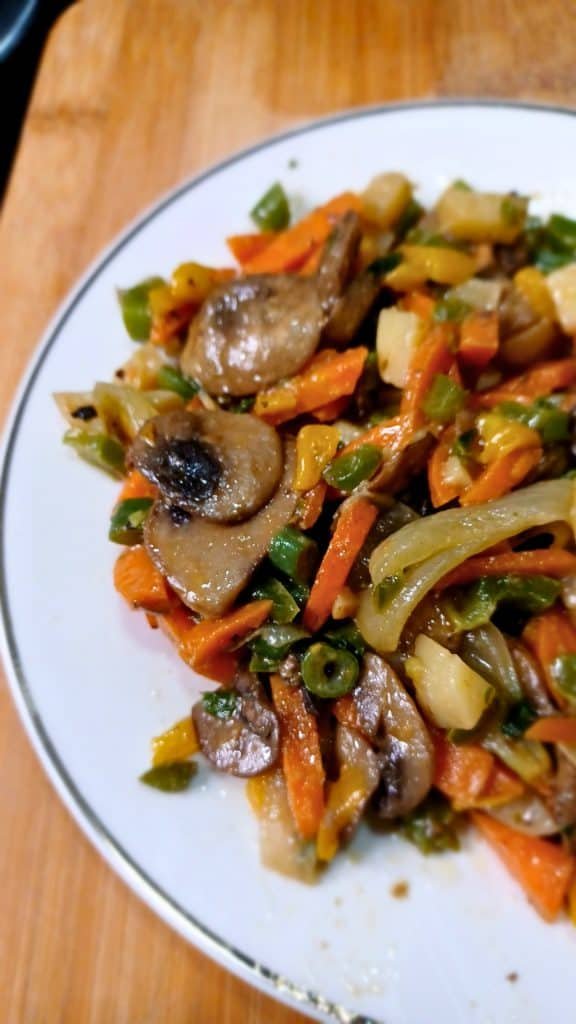 Mushroom stir fry in a white plate on a wooden board.