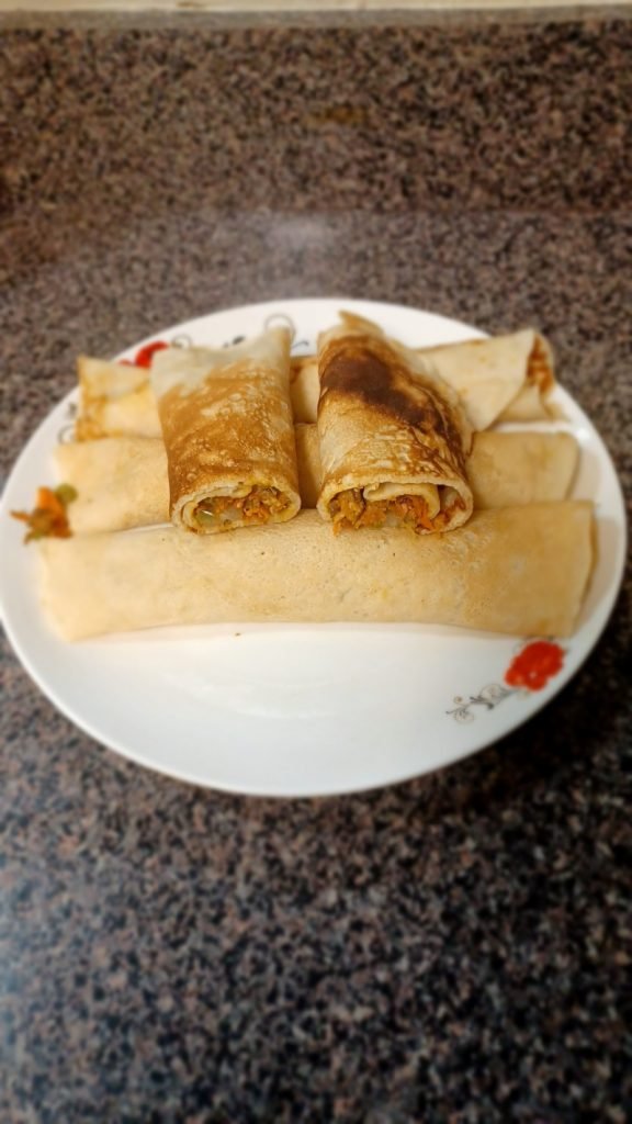 Pancake rolls in a white dish on a gray kitchen slab.