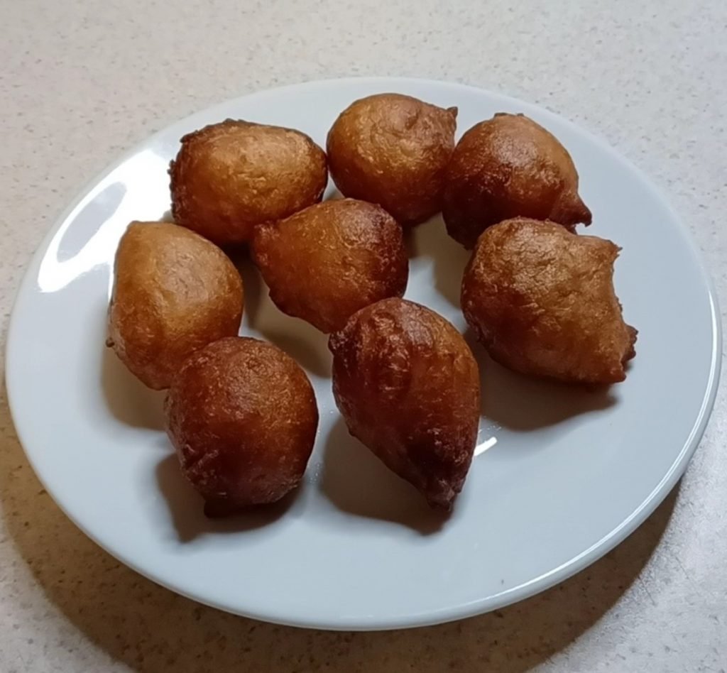 Puff puff in a white dish on a white kitchen slab.