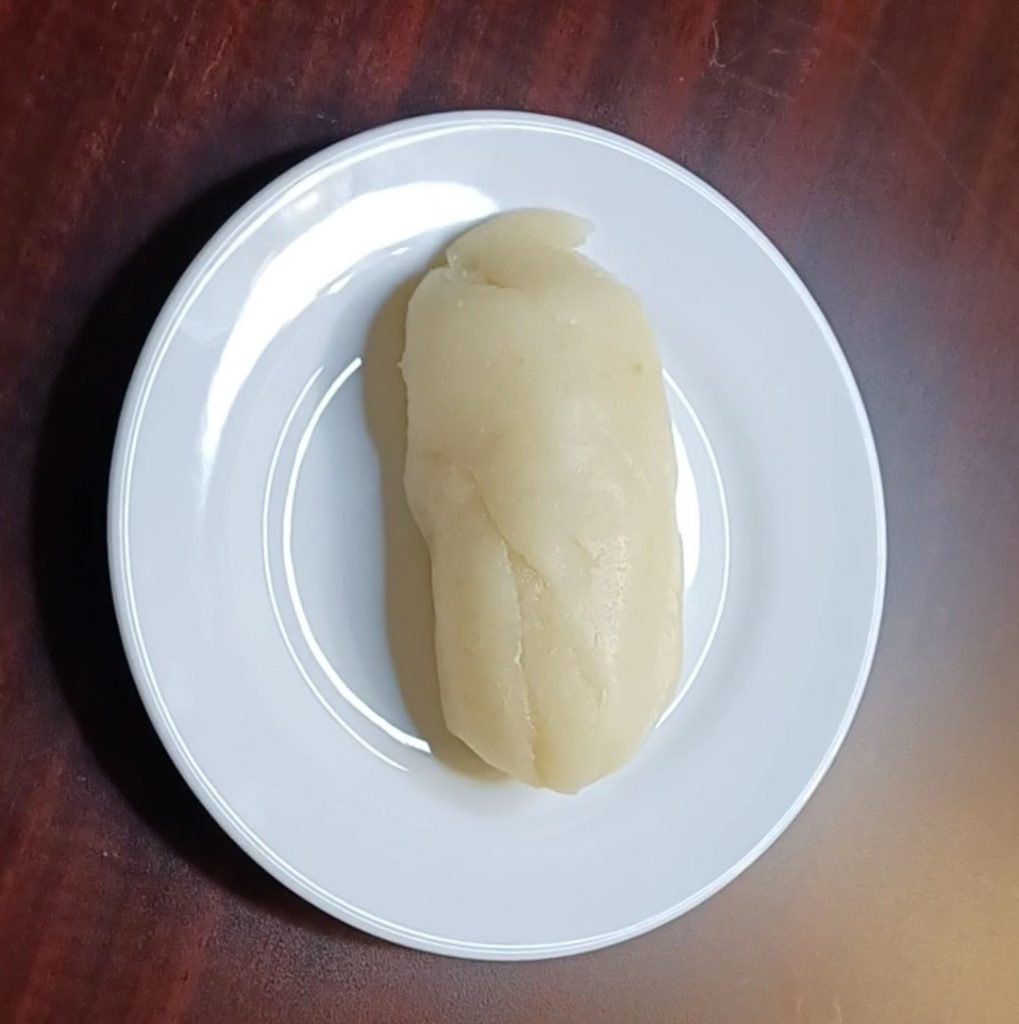 Water fufu in a white dish on a brown table.